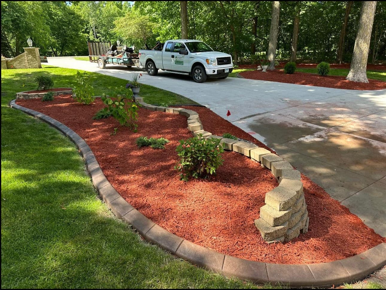 Landscape design with mulch beds, stone borders, and a work truck in a residential yard.