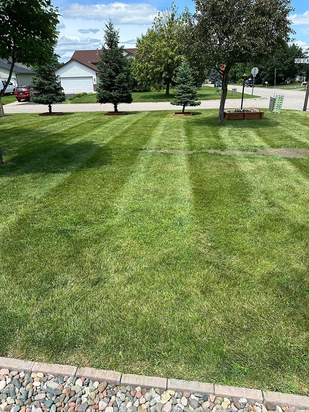 well-maintained lawn with striped mowing pattern, trees, and landscaping features