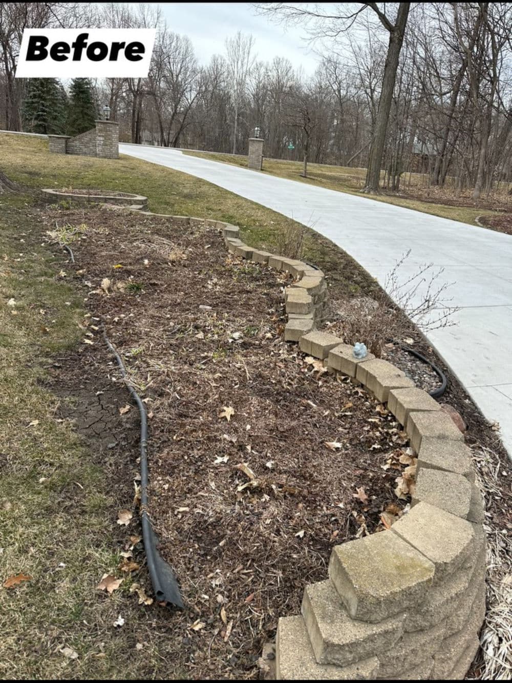 Before garden landscaping transformation featuring a curved stone border and bare soil.